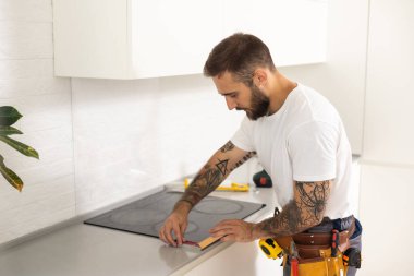 craftsman installs hob in kitchen. Household Appliance Installation Services Concept.