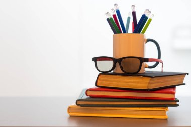 Bir yığın kitap ve kalemli bir kupa..