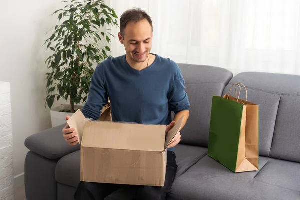 Schöner Junger Mann Öffnet Schachtel Mit Paket Während Hause Auf — Stockfoto