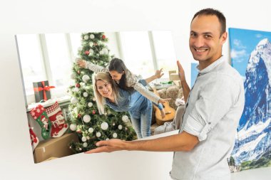 Bir adam bir resim tuvalinde Noel fotoğrafı tutuyor..