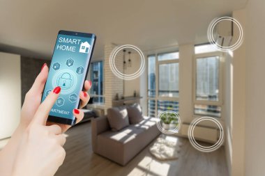 Akıllı bir evle ev ısısını kontrol etmek, telefonla yakın çekim yapmak. Evdeki akıllı aygıtları yönetmek için akıllı ev ve mobil uygulama kavramı.