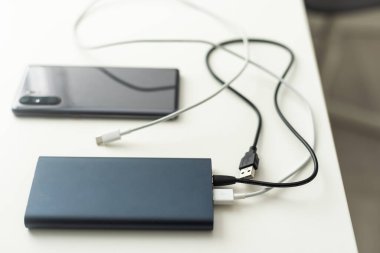 powerbank ve ahşap masa üzerinde cep telefonu.