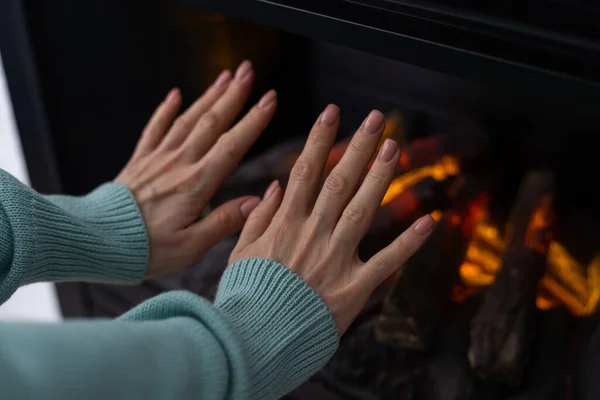 hand in front of an electric heater, inside an apartment in winter.
