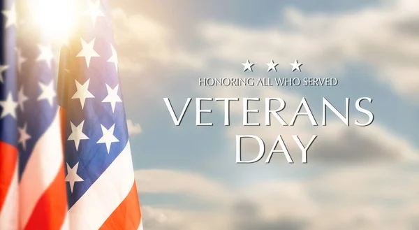 American flags with Text Veterans Day Honoring All Who Served on sunset background. American holiday banner. High quality photo