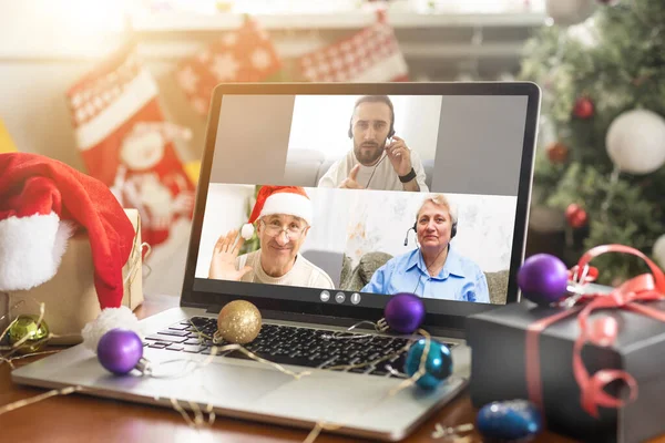 Virtual Christmas tree meeting team teleworking. Family video call remote conference. Laptop webcam screen view. Team meet working from their home offices.