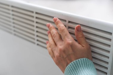 Kadın eli beyaz radyatörde. Isıtma mevsimi. Enerji krizi. Soğuk piller. Merkezi ısıtma.