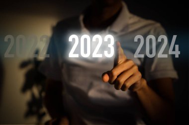 Parmak, gri arkaplanda sanal arayüzde, metin için kopyalama alanı olan 2023 düğmesine basar. Yeni yıl kavramı. İş adamı 2023 'e baskı yapıyor. Yeni Yıl Başlıyor 2023