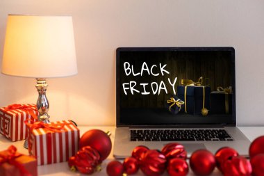 Kara Cuma alışveriş konsepti laptoplarda bulanık yılbaşı ışıklarına karşı siyah ekranda yazılmış.