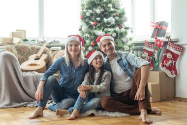 Aile içeride Noel ağacının yanında eğleniyor ve oyun oynuyor.