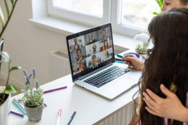 Teen girl distance learning virtual distance online class on video call virtual lesson with mother, studying at home using laptop computer. Parent or tutor helping child daughter 