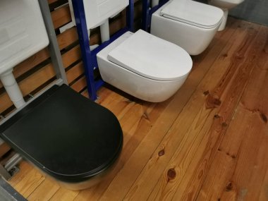 Tesisat dükkanının deposunda arka arkaya duran beyaz klozet örneklerinin sergilenmesi. Tuvalet için modern hijyenik malzeme örnekleri. Tesisat mağazasında yeni modern tuvalet.