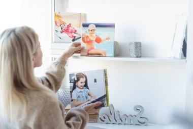 Young woman hanging a photo canvas print painting on the wall. clipart