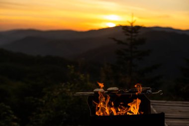 Geceleri odun yakmak. Dağlardaki turistik kamplarda kamp ateşi. Alevler soyut arka planda kıvılcımlar saçıyor. Dışarıda ızgara yapıyorum. Cehennem ateşi elementi. Yakıt, güç ve enerji