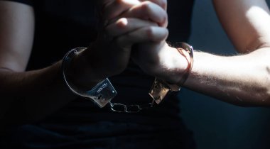 male hands in handcuffs black background.