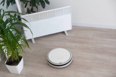 Robot elektrikli süpürge plastik zemine sürüp kaldırıyor. Akıllı Ev. Ev asistanı kavramı