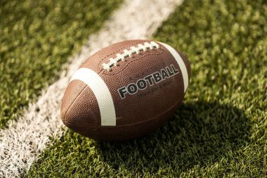 American football ball on the grass of a stadium.