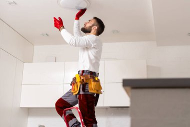 Apartmanın içine elektrik lambaları döşeyen elektrik işçisi. İnşaat dekorasyonu kavramı