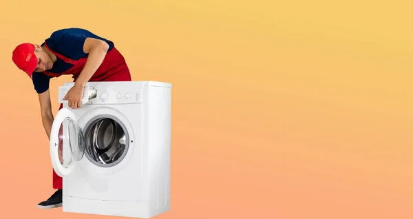 Tamirci Turuncu Arka Planda Bir Çamaşır Makinesini Tamir Ediyor — Stok fotoğraf
