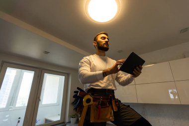 Installation lighting. Builder is holding a tablet in his hands. Concept - lighting engineer. Process installing. Electrician.