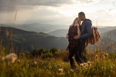 Turist ekipmanlı bir adam ve bir kadın bir kayanın üzerinde durup panoramik manzaraya hayran kalıyorlar. Birbirine aşık bir çift güzel manzaraya hayran. Birbirine aşık bir çift seyahat ediyor. Yürüyüşe çıkmış bir çift.