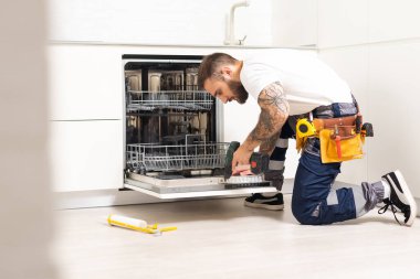 Bir evde bulaşık makinesini tamir eden teknisyen ya da tesisatçı..