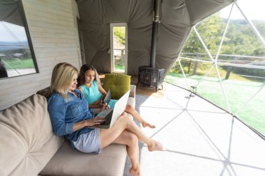 mother and daughter with laptop and tablet on sofa.