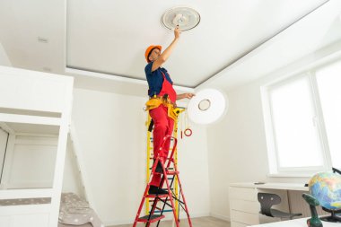 İşçi evin tavanına lamba yerleştiriyor. Metin için boşluk.