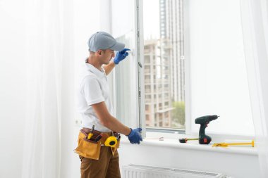 a repairman repairs, adjusts or installs metal-plastic windows in the apartment. glazing of balconies, loggias, verandas in house. production of double-glazed windows to individual sizes