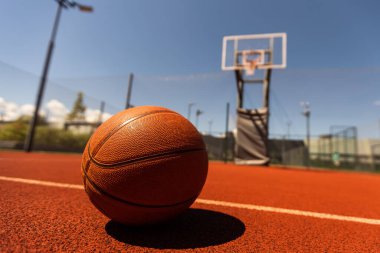 Top view orange ball for basketball lying on the rubber sport court. Sport red ground outdoor in the yard.