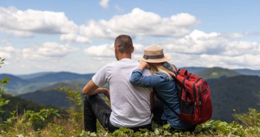 Hikers with backpacks relaxing on top of a mountain and enjoying the view.