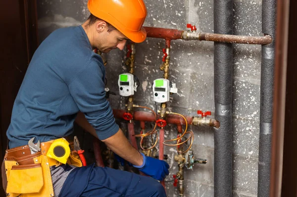 Maintenance engineer checking technical data of heating system equipment in a boiler room. Plumber installing pressure meter for house heating system.