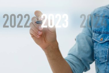 Parmak, gri arkaplanda sanal arayüzde, metin için kopyalama alanı olan 2023 düğmesine basar. Yeni yıl kavramı. İş adamı 2023 'e baskı yapıyor. Yeni Yıl Başlıyor 2023