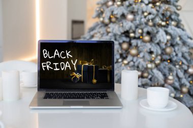 Kara Cuma alışveriş konsepti laptoplarda bulanık yılbaşı ışıklarına karşı siyah ekranda yazılmış.