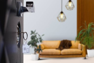 Yeni bir eve açılan kapı. Anahtarlı kapı kolu ve ev şeklindeki anahtarlık. İpotek, yatırım, gayrimenkul, mülk ve yeni konut kavramı