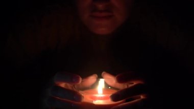 Mum siyah elbiseli güzel bir kadın tarafından tutulan bir bardakta yakılıyor. Dünya enerjisini saklama kavramına göre izole edilmiş. Dünya saati.