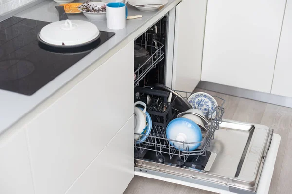 a stack of dirty dishes is on the door of the dishwasher