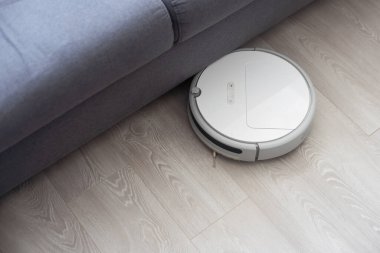 Odadaki kanepenin yanındaki modern robot elektrikli süpürge..