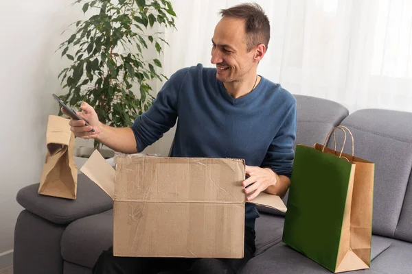 Handsome Young Man Opening Box Parcel While Sitting Sofa Home — Stock Photo, Image