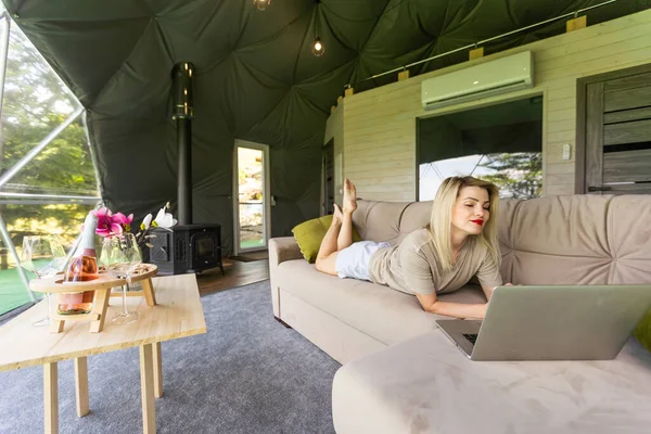 stock image middle aged woman uses a laptop resting and spending time at Glamping house on holidays. holiday dome tent. Cozy, camping, hygge, lifestyle concept.