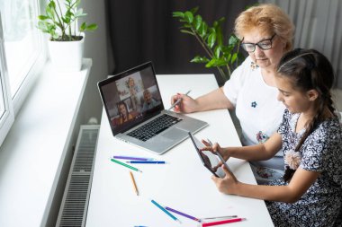 Mutlu büyükannesi ve torunu evde bilgisayarla görüntülü konuşma yapıyorlar.