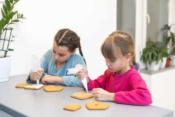 stock image two cute sisters make and decorate cookies.