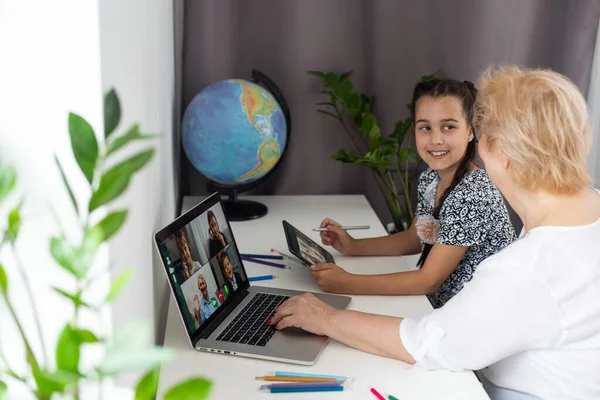 stock image Happy mature grandmother with adorable little granddaughter using tablet at home together, excited middle aged woman and cute kid looking at device screen.