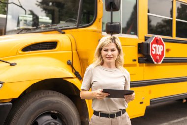 Female Teacher Or Student With Digital Tablet near the school bus. video chat.