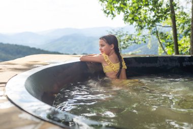 little girl in a hot tub in the mountains, summer.