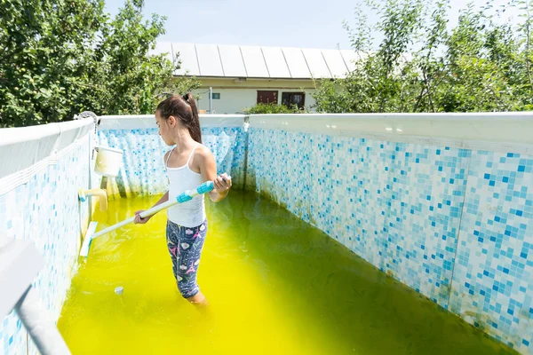 a little girl cleans a very dirty pool.