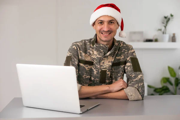 ノートパソコンを持ったサンタの帽子の軍人 — ストック写真