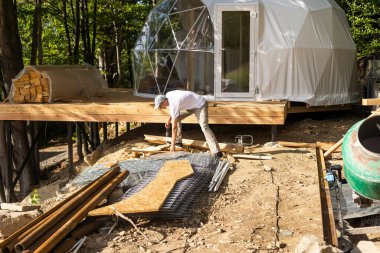 the master builds the dome. Outside spherical glamping dome. Hemispherical structure lattice shell geodesic polyhedron. Camping house hotel party tent