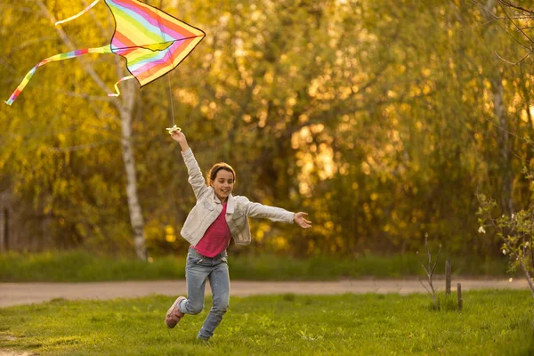 Little girl flying a kite running outdoor with a kite.