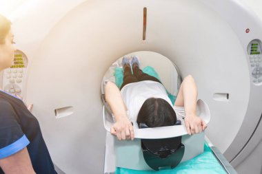 Bir kadın tomografi masasında yatıyor. Kadın, modern bir hastanede bilgisayarlı tomografi muayenesinden geçiyor..