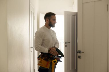 Ön ahşap giriş kapısına bir kilit takıldı. Kapı tokmağı monte eden mavi üniformalı genç çilingir işçisinin portresi. Profesyonel tamir servisi. Bakım Kavramı.